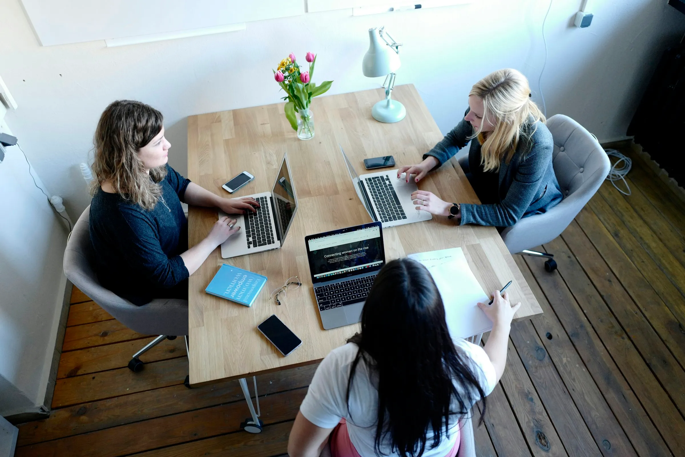 Equipe reunida em volta de uma mesa de trabalho, com notebooks e anotações.