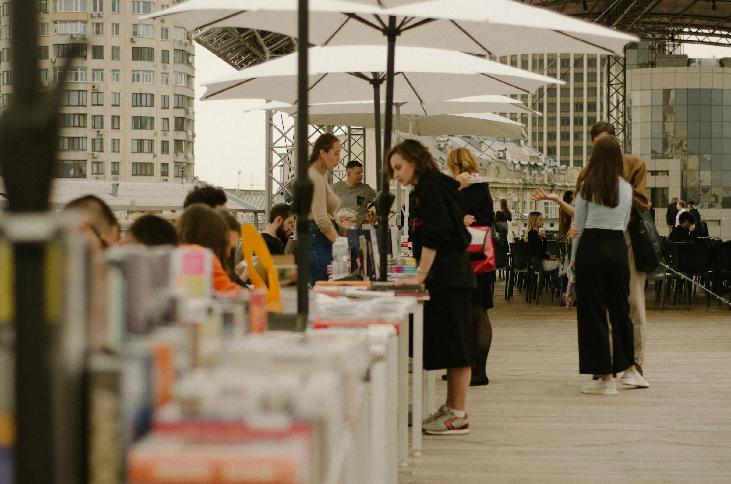 Público circula entre bancas de livros sob tendas brancas em uma feira ao ar livre.